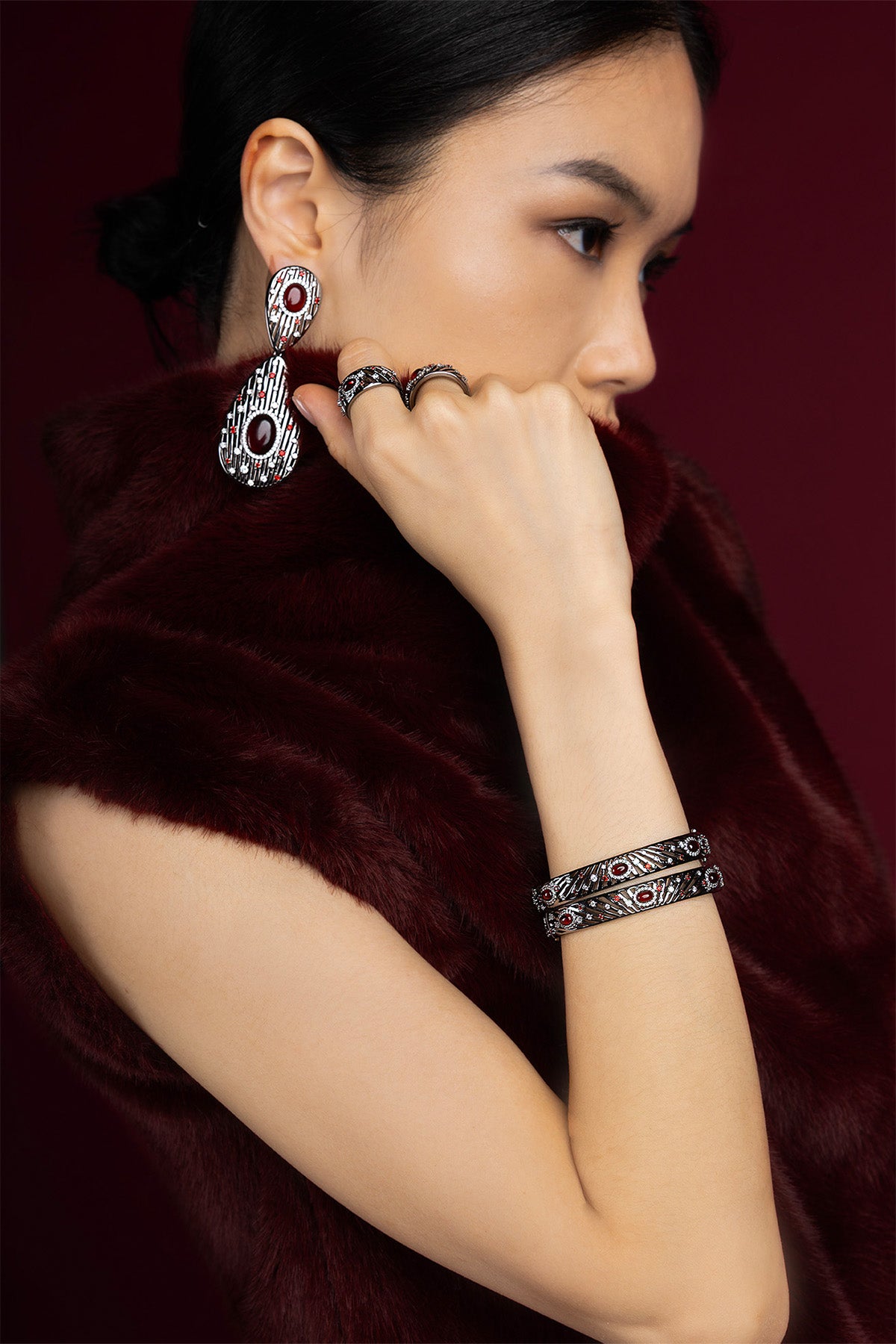 Femme portant les bijoux APM Monaco, une élégance mystérieuse aux reflets rouges profonds.
