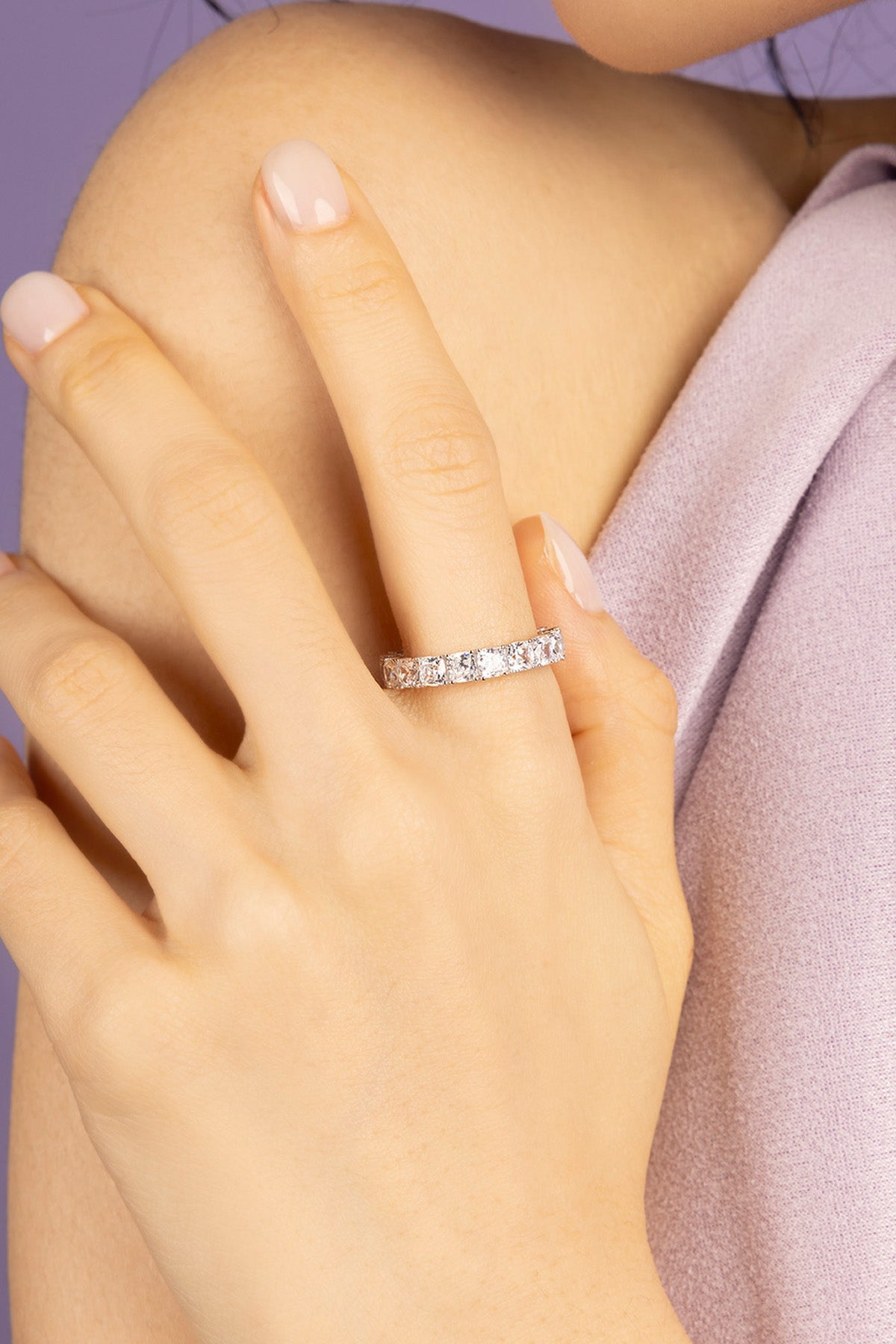 Hand wearing APM MONACO silver ring on a white background
