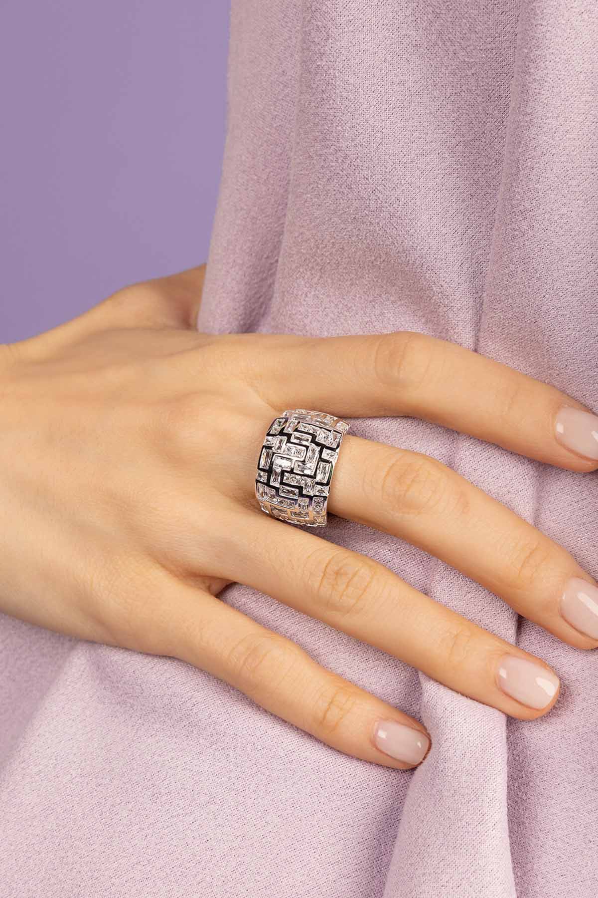 Close-up of a hand wearing two silver chunky rings from APM MONACO on a white background