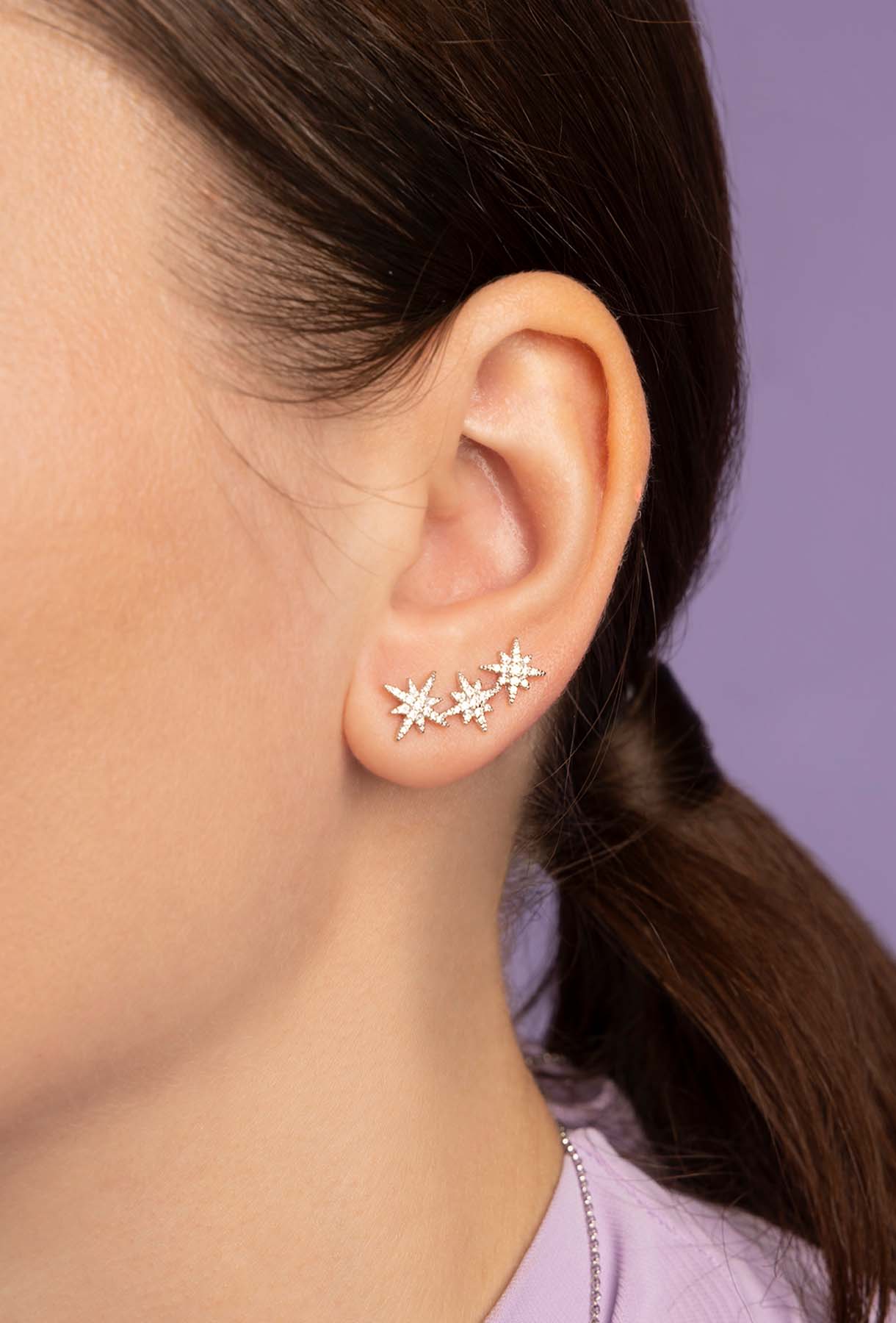Close-up of an ear wearing star-shaped earring with a neutral background