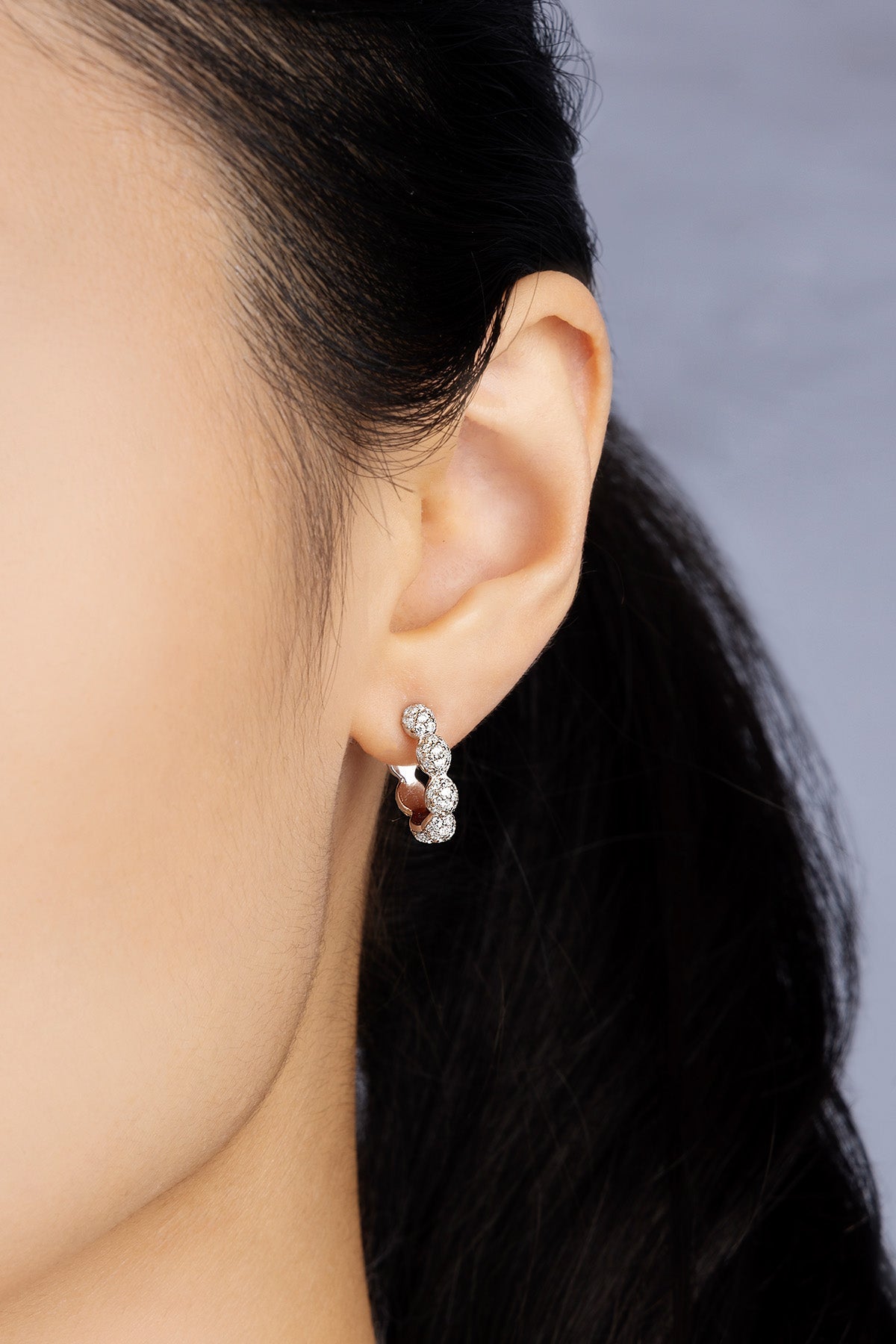 Close-up of an ear wearing a silver earring with a blurred background