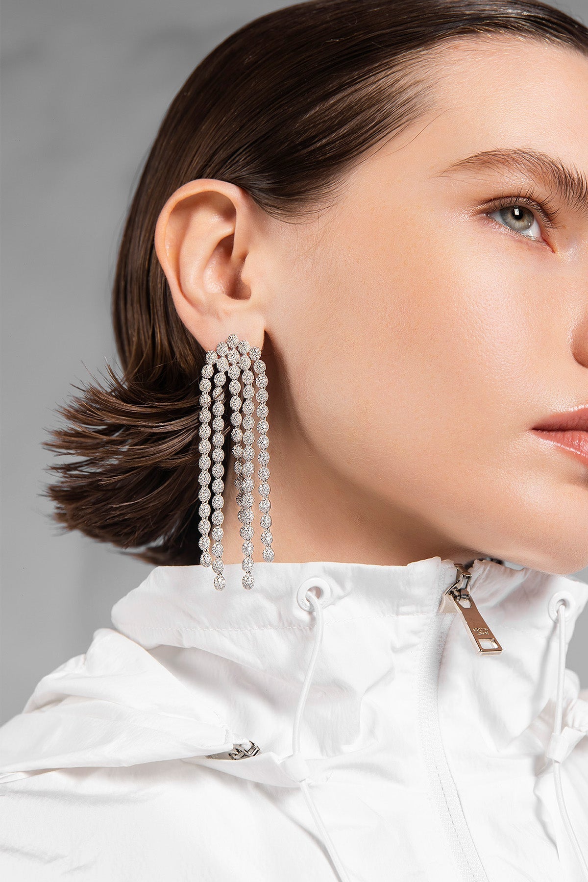 Close-up of a woman wearing APM MONACO silver pave cascade earrings
