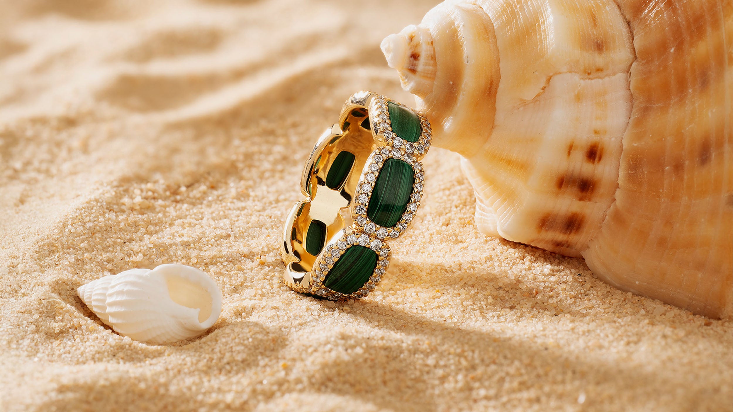 APM MONACO yellow gold ring with green stone on sand