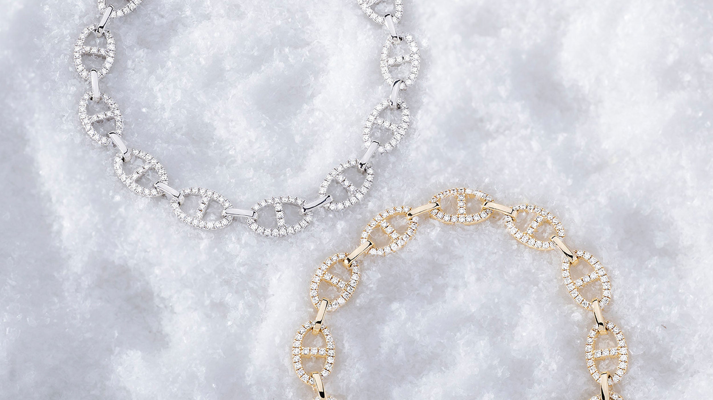 APM MONACO yacht club bracelets on snowy surface, one in silver and one in yellow gold