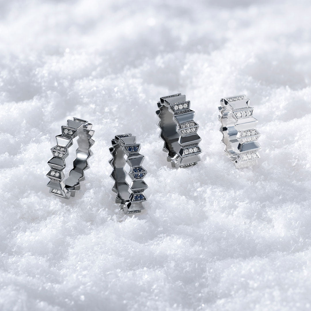 Four APM MONACO up ad down rings on snowy surface, three in dark grey and one in silver with white stones