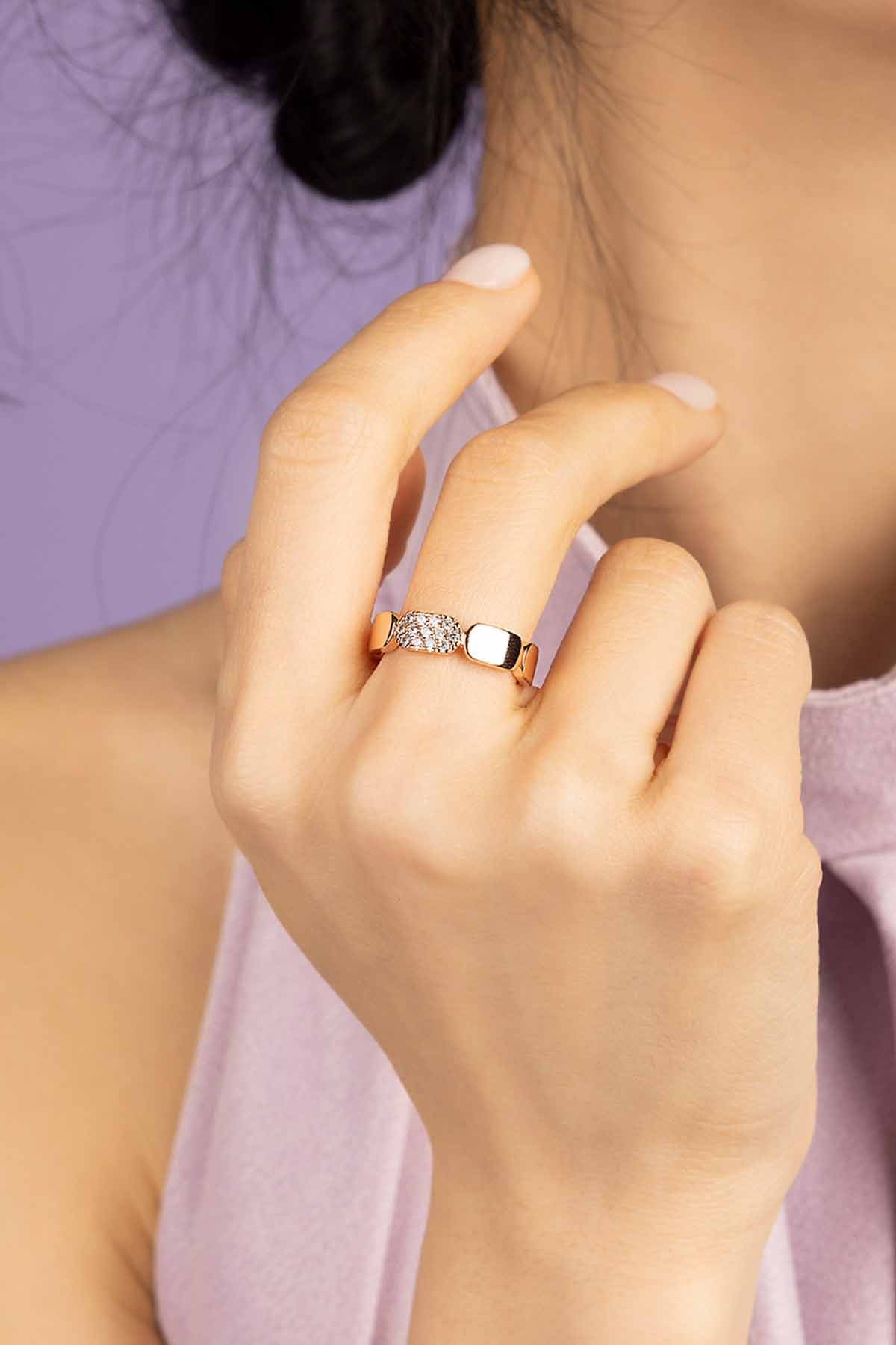 Close-up of a hand wearing a diamond ring on a dark fabric background